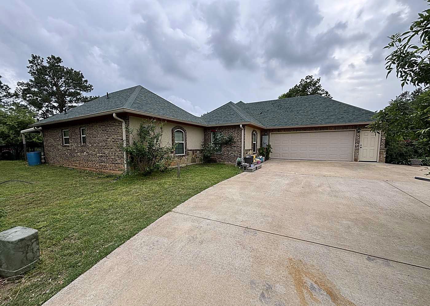 Long brick ranch home with a new roof above a wide driveway