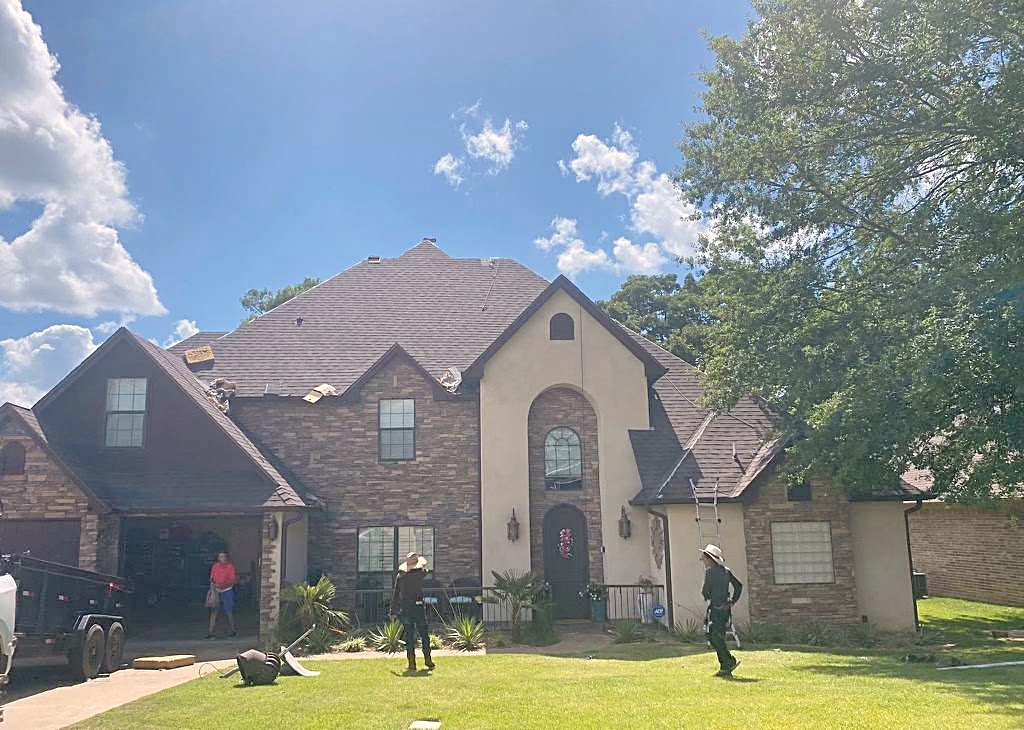 AR Global Roofing crew in the front yard of a stone and stucco home under its new roof
