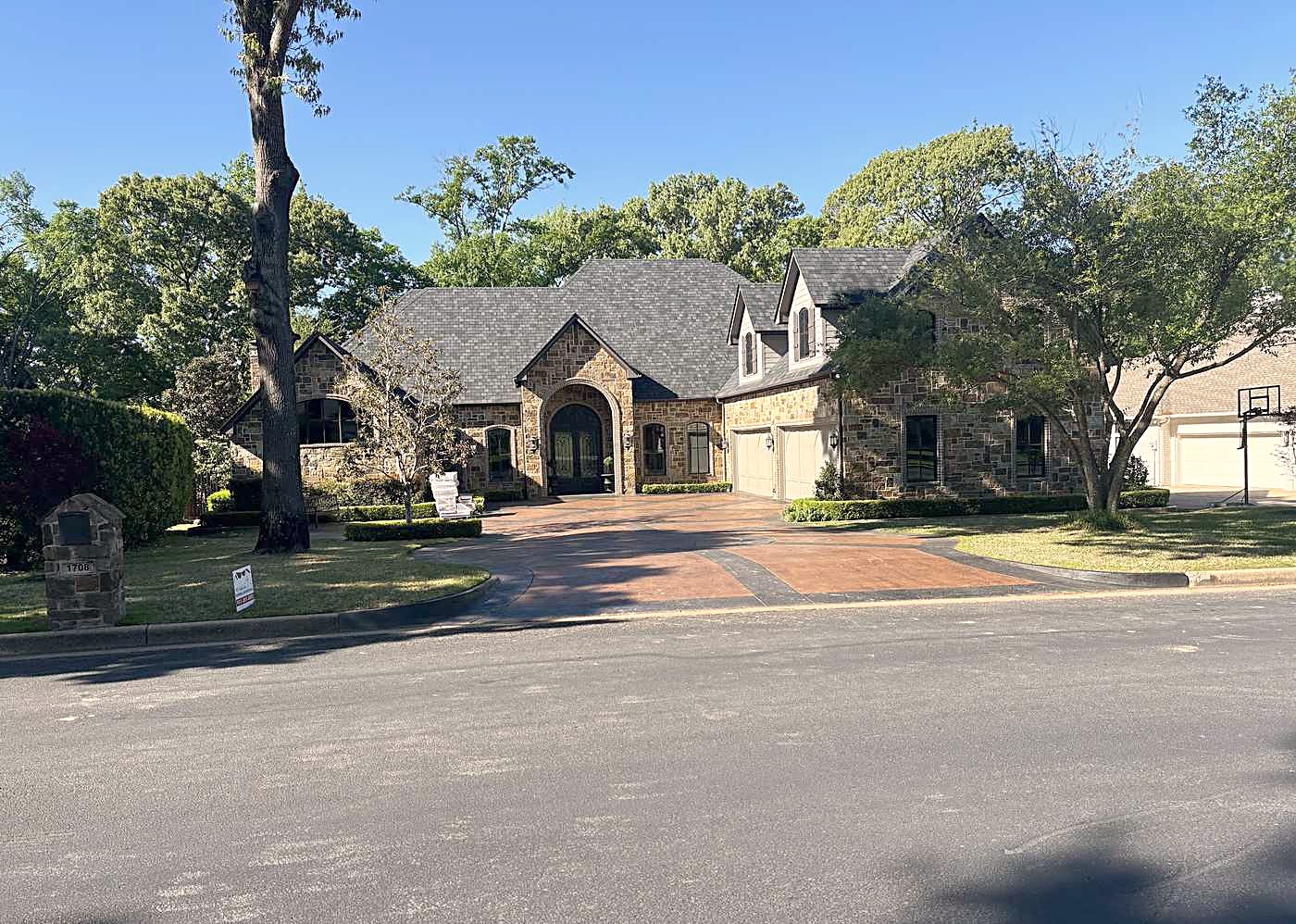 Wide stone home with a new roof seen from the street